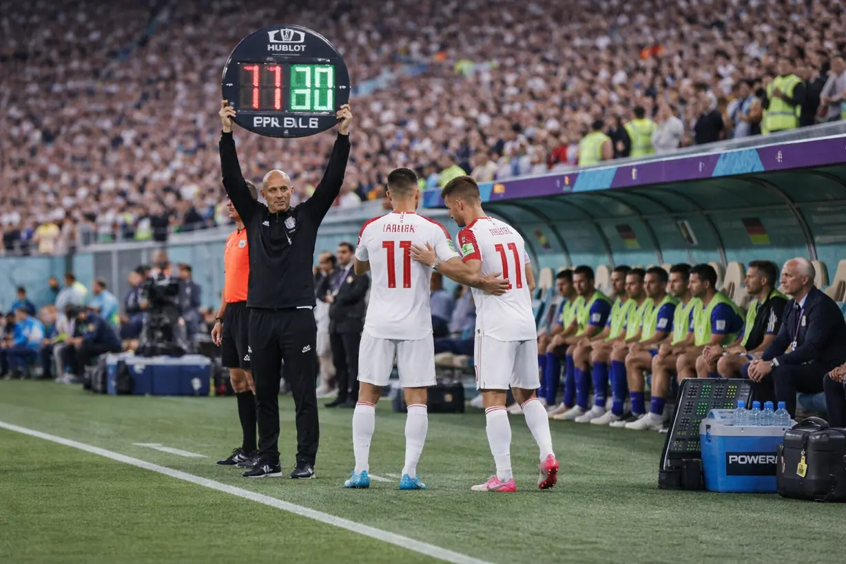 世界杯比赛中进行换人操作，教练举起换人牌，替补球员准备登场